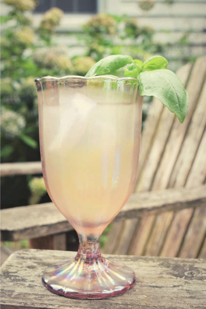 easy fresh basil lemonade in a pink glass on the patio