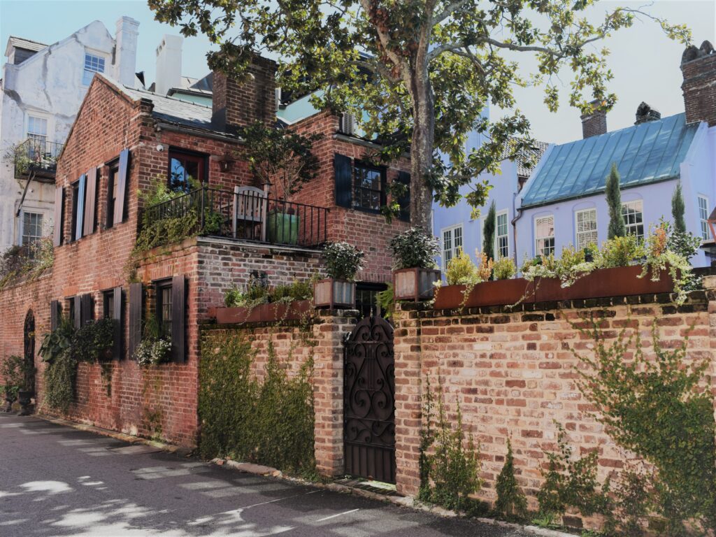 slow travel Charleston south, charleston south carolina southern historic travel red brick house old vines alley terrace balcony patio downtown black shutters plants foliage