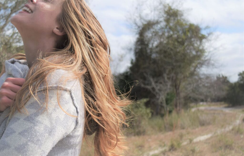 ways to enjoy winter, girl with long hair smiling in gray sweater, southern, marshes, cold, bright, mindful living modern old soul