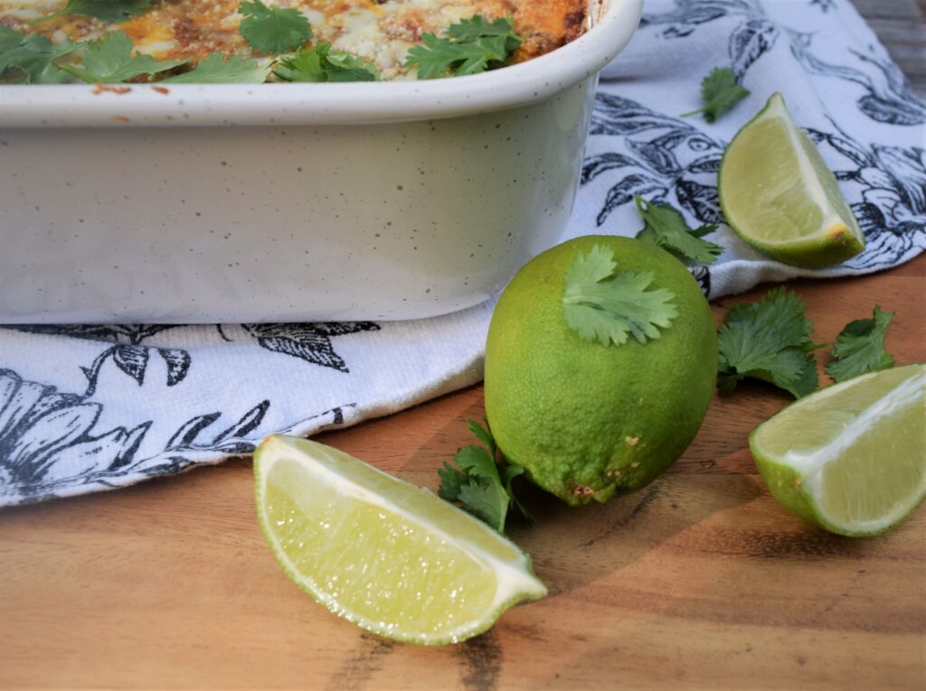 mexican lasagna comfort food spicy hispanic casserole cilantro limes on wood board close up farmhouse flower towel black and white